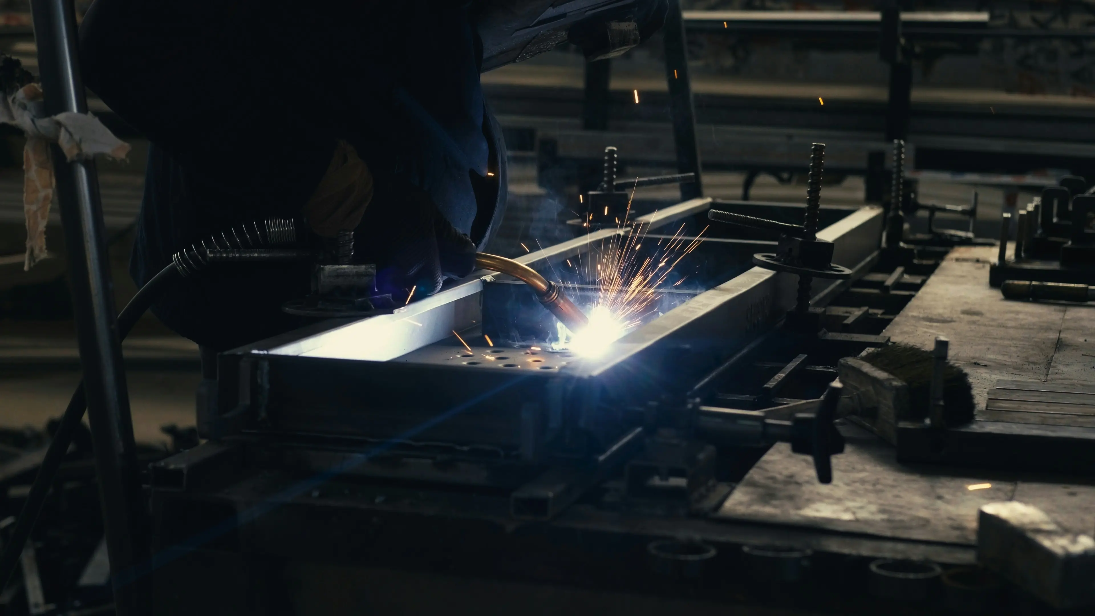 Soldador trabajando con soldadura MIG en un taller industrial
